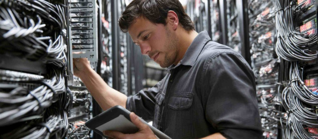 Data centre engineer performing maintenance in server room with tablet