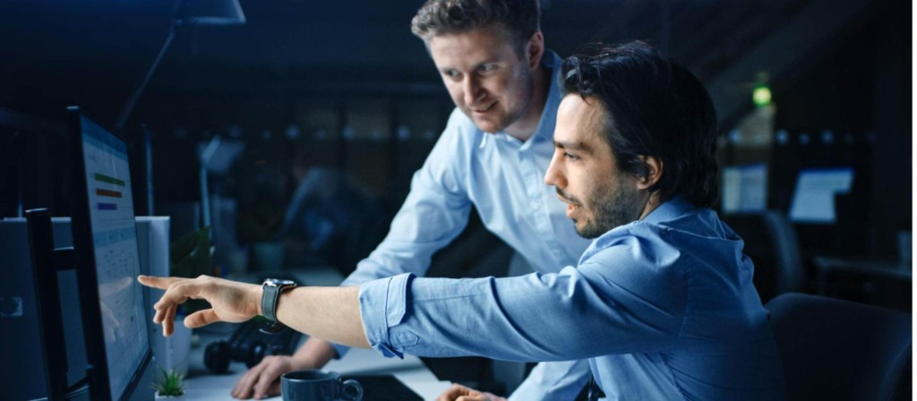IT engineers reviewing system monitoring dashboard at night