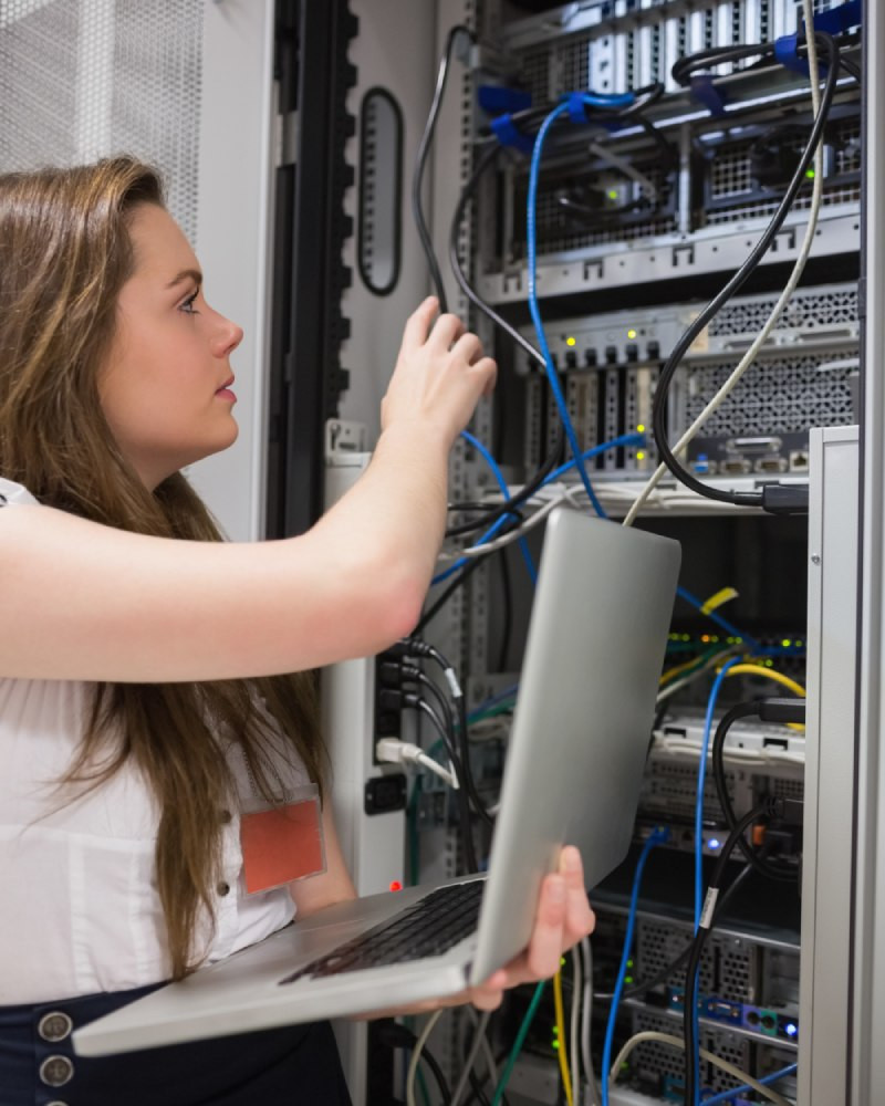 System integration engineer connecting cables in server rack with laptop
